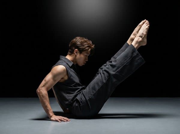 AI portrait of an attendee holding a difficult balance pose on a dark stage